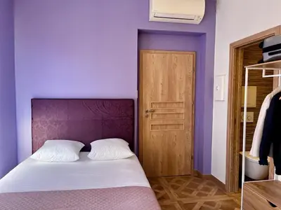 a purple bedroom with a bed and a wooden door at Studio Lavande cosy et central à Cagnes-sur-Mer in Cagnes-sur-Mer