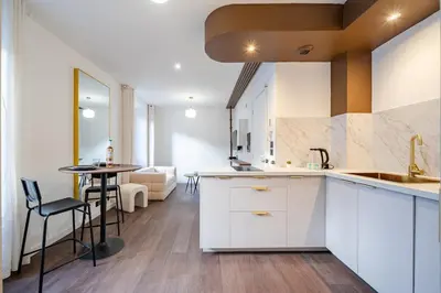 a kitchen with white cabinets and a table in a room at Appartement cosy au coeur de Cagnes sur Mer in Cagnes-sur-Mer