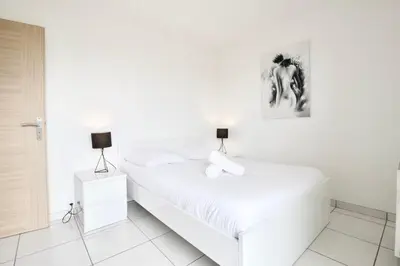 a white bedroom with two beds and a picture at Terrasse, piscine & parking sur la Côte d'Azur in Saint-Laurent-du-Var