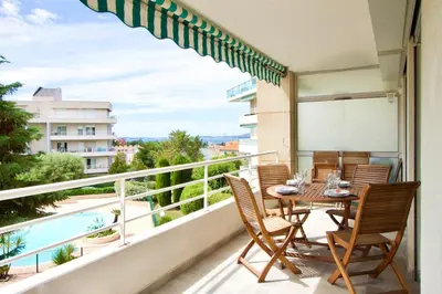 a balcony with a table and chairs and a pool at Terrasse, piscine & parking sur la Côte d'Azur in Saint-Laurent-du-Var