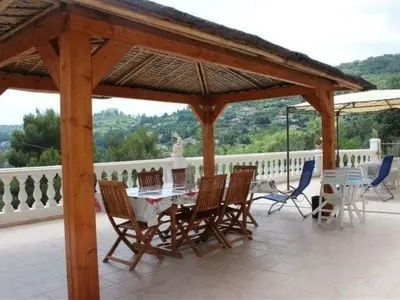 a wooden pavilion with a table and chairs on a patio at Holiday Home Rocabel mit Blick auf das Wasser by Interhome in Gattières