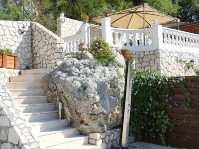 a white fence with stairs and a rock with flowers at Holiday Home Rocabel mit Blick auf das Wasser by Interhome in Gattières