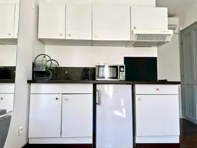 a kitchen with white cabinets and a microwave at Studio cosy proche des plages & promenade in Nice