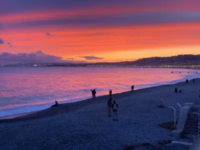a group of people on a beach at sunset at Sea view appartment in Nice