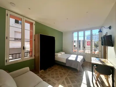 a bedroom with a bed and a couch and windows at Studio Olivier avec terrasse à Cagnes-sur-Mer in Cagnes-sur-Mer