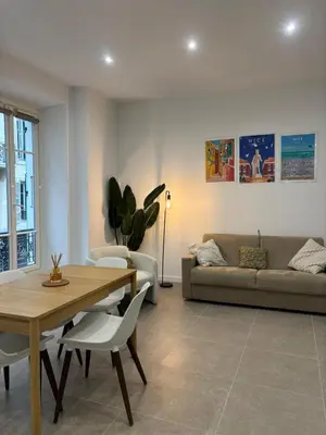 a living room with a table and a couch at Le Notre Dame - 2 pièces au cœur de Nice in Nice