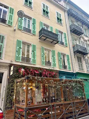a building with green shutters and flowers in front of it at Le Notre Dame - 2 pièces au cœur de Nice in Nice