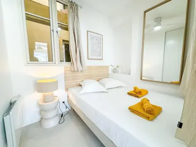 a white bedroom with a bed and a mirror at Confortable & Élégant climatisé au Port de Nice in Nice