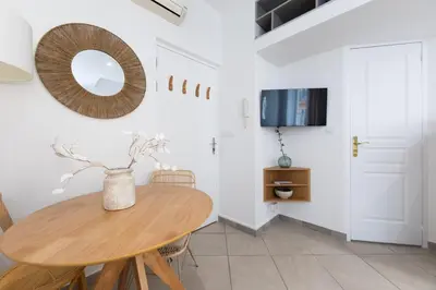 a dining room with a wooden table and a tv at Coup de cœur 3 couchages Quartier du Port in Nice
