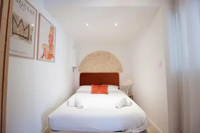 a bedroom with a white bed with an orange pillow at Confort, modernité & calme au Port de Nice in Nice