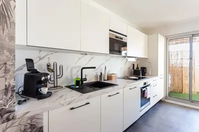 a white kitchen with white cabinets and a sink at WeHost- CORNICHE Soleil Couchant 2 chambres 4pers,Parking,Piscine in Nice