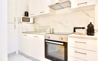 a white kitchen with a stove and a microwave at Magnifique appartement rénové au port de Nice in Nice