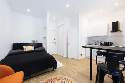 a bedroom with a bed and a table and a kitchen at Studio Cosy et confortable hyper centre in Nice