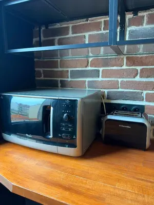 a microwave sitting on a counter next to a brick wall at Renovated 2-room apartment Sleeps 4 Tram and shops nearby in Nice