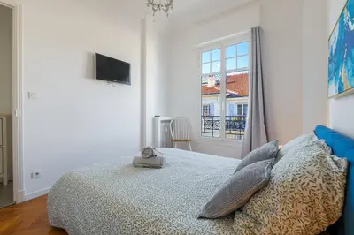 a white bedroom with a bed and a window at Charmant 2 pieces dans le carre d or in Nice