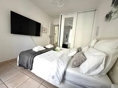 a bedroom with a white bed with a flat screen tv at Le MIAMI in Nice