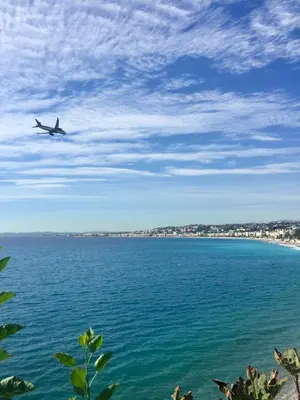 a plane flying over the water with a beach at Le MIAMI in Nice