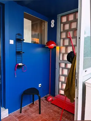 a room with a blue wall and a red lamp at Holidays 80 in Saint-Laurent-du-Var