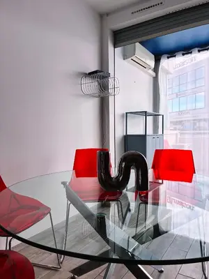 a glass table with two red chairs and a glassigunigunigunigun at Holidays 80 in Saint-Laurent-du-Var