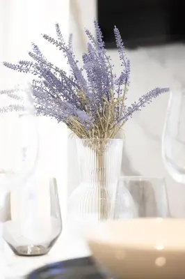a white vase with purple flowers in it on a table at Duplex moderne climatisé Carré d'or in Nice