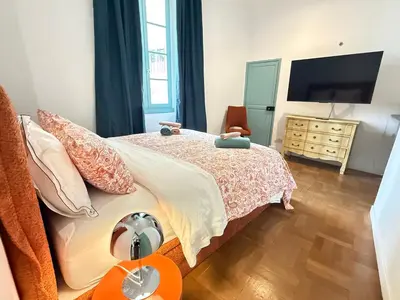 a bedroom with a bed and a dresser with a television at La Rotonde Art,elegance & romantisme au Coeur de Nice, à 2 pas du Negresco in Nice