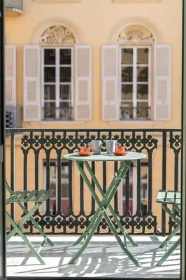 a table with two cups on top of a fence at La Perle de Masséna in Nice