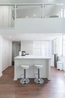 a kitchen with a white counter and two stools at La Perle de Masséna in Nice