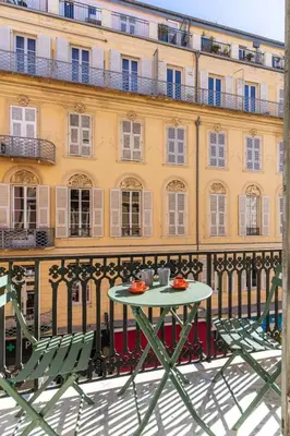 a table and chairs on a balcony in front of a building at La Perle de Masséna in Nice