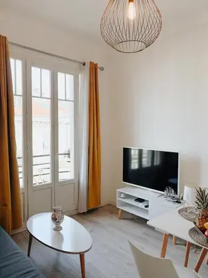 a living room with a tv and a table at Elegant Apartment with Balcony, Central Nice in Nice