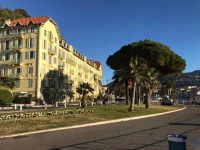 a building on a street with palm trees and a road at Appartement 3P Nice port Sea view in Nice