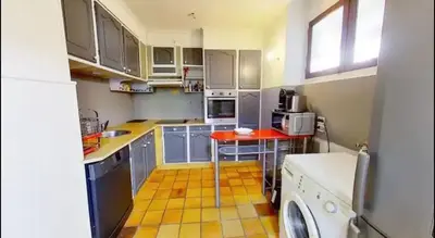 a kitchen with blue cabinets and a red table at Nice collines in La Trinité