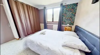 a bedroom with a bed with a blue headboard and a window at Nice collines in La Trinité