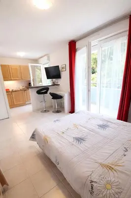 a bedroom with a large bed and a kitchen at Cocoon au calme, proche mer et centre ville in Nice