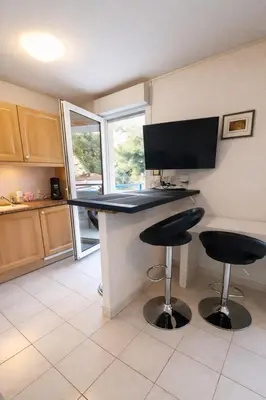 a kitchen with a desk with two stools and a monitor at Cocoon au calme, proche mer et centre ville in Nice