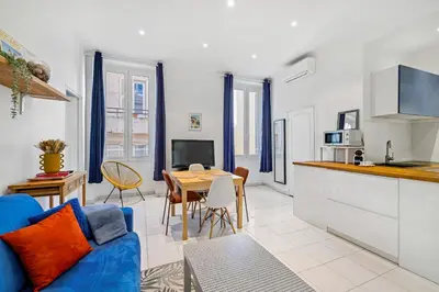 a kitchen and living room with a blue couch and a table at Nice Renting - GRIMALDI - Golden Square Best Location Fully Equiped in Nice