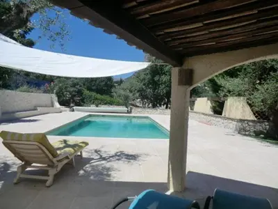 a swimming pool with a chair and a umbrella at Nice Petite maison mitoyenne avec piscine in La Gaude