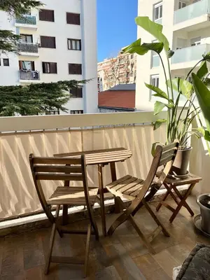 a wooden table and two chairs on a balcony at Charming 2 rooms with balcony in Nice