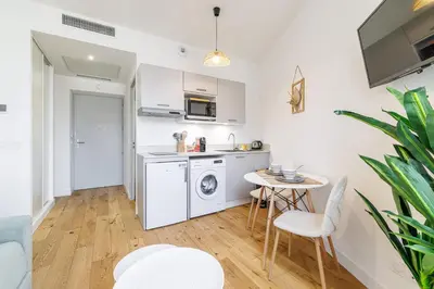 a kitchen with a washing machine and a table at Charming City Center Studio 402 in Nice