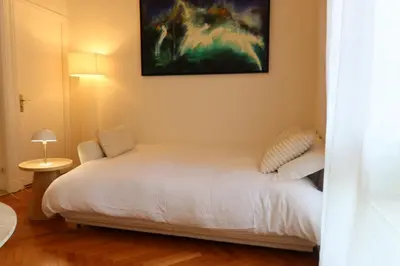 a bedroom with a white bed and a painting on the wall at Quiétude - Studio calme avec vue jardin en hyper centre de Nice in Nice