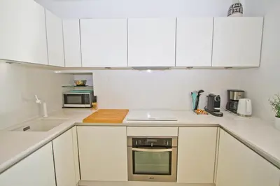 a white kitchen with white cabinets and appliances at Le Copacabana Riviera in Nice