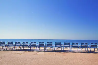 a row of blue chairs sitting on the beach at Le Copacabana Riviera in Nice
