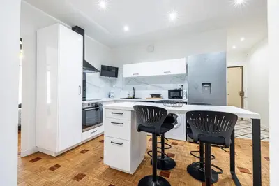 a kitchen with a white counter and two black chairs at Chambre privée 1 personne BAIL MOBILITE in Nice