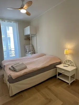 a bedroom with a large bed with a lamp and a table at Cozy Apartment in the heart of Nice in Nice