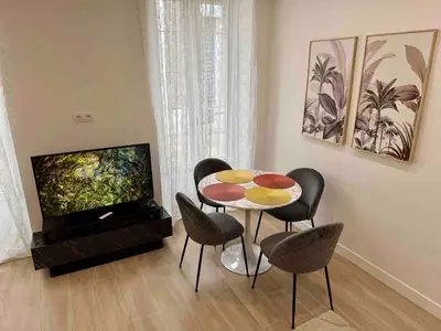 a living room with a table and chairs and a television at Nikaia Residence - 2BR Central Nice Close to Everything in Nice