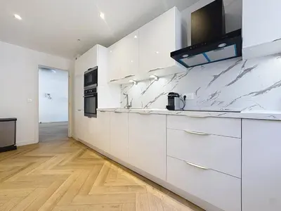 a white kitchen with marble counter tops and appliances at Appartement chic avec balcon Carré d Or Nice in Nice