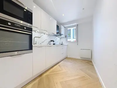 a kitchen with white appliances and a wooden floor at Appartement chic avec balcon Carré d Or Nice in Nice