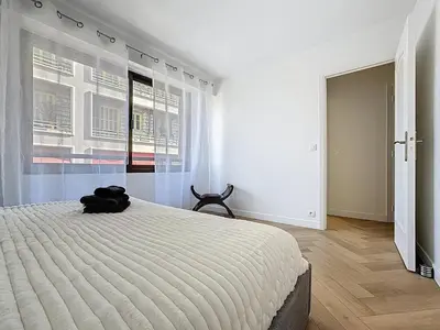 a white bedroom with a large bed and a window at Appartement chic avec balcon Carré d Or Nice in Nice