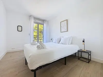 a white bedroom with a large bed with a window at Comfort and relaxation and swimming pool in Nice