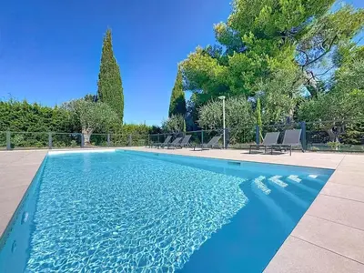 a blue swimming pool with chairs and trees at Comfort and relaxation and swimming pool in Nice