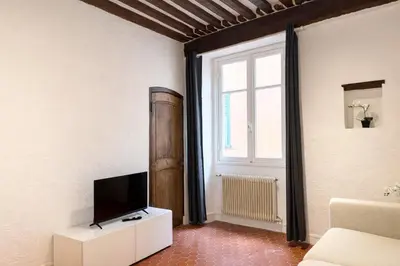 a living room with a television on a white cabinet at Charme du Vieux-Nice - cocon lumineux à 100 m de la mer in Nice